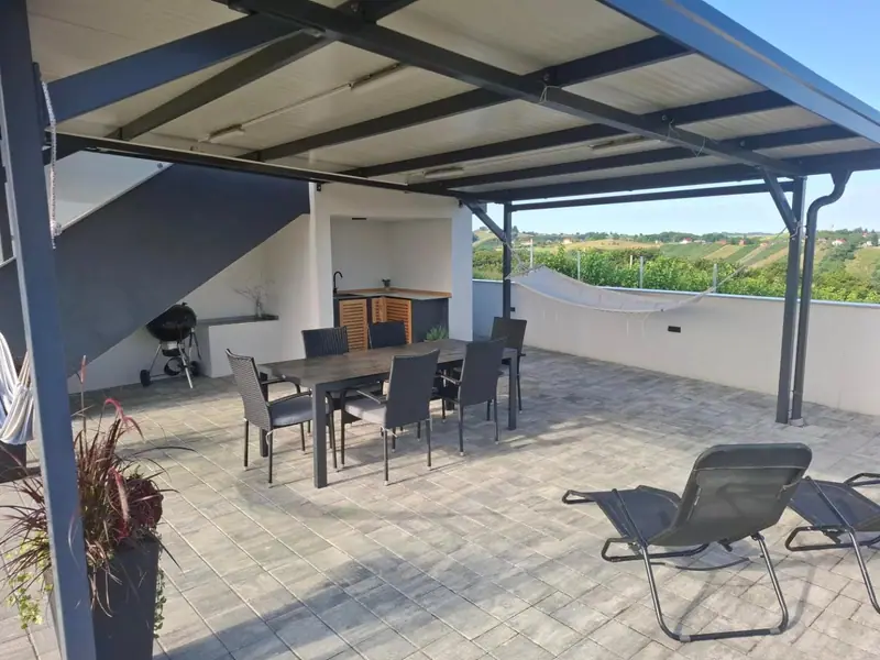Natkrivena terasa s ležaljkama i blagovaonskim stolom