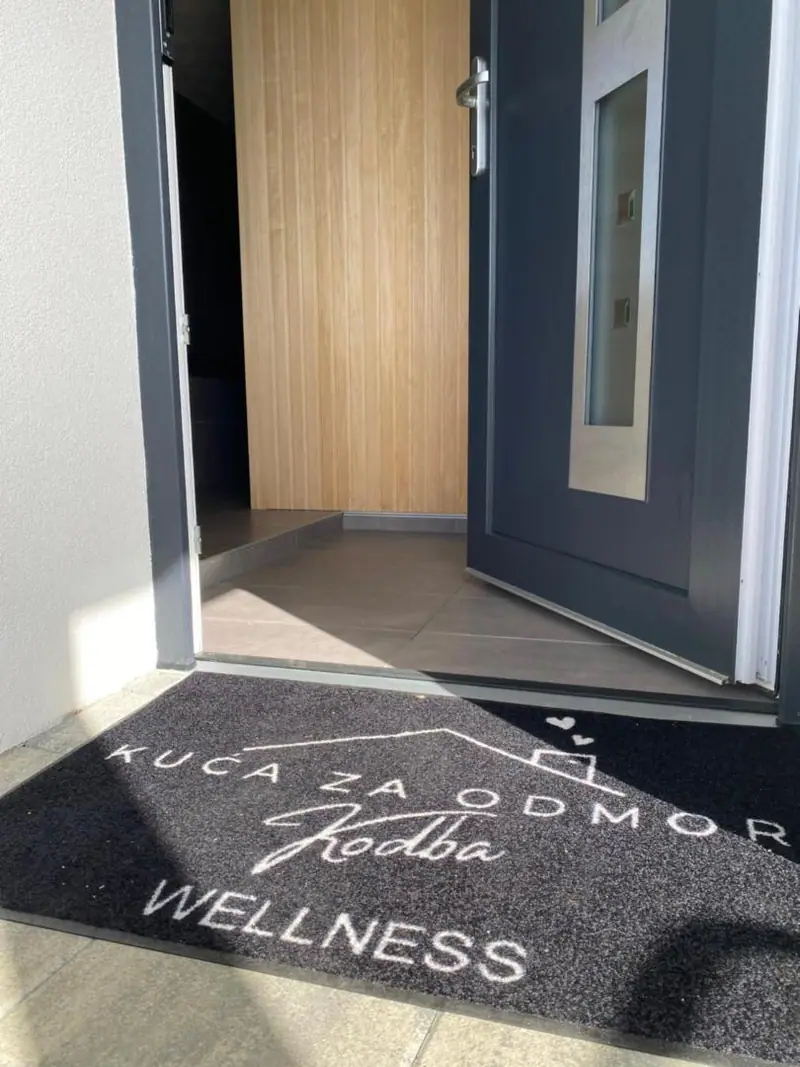 Ulaz u kuću s otiračem s natpisom Kuća za odmor Kodba Wellness